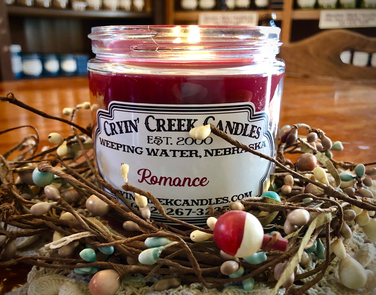 Cryin' Creek Candles wooden wickcandle 'Romance' in a decorative setting with branches and berries.