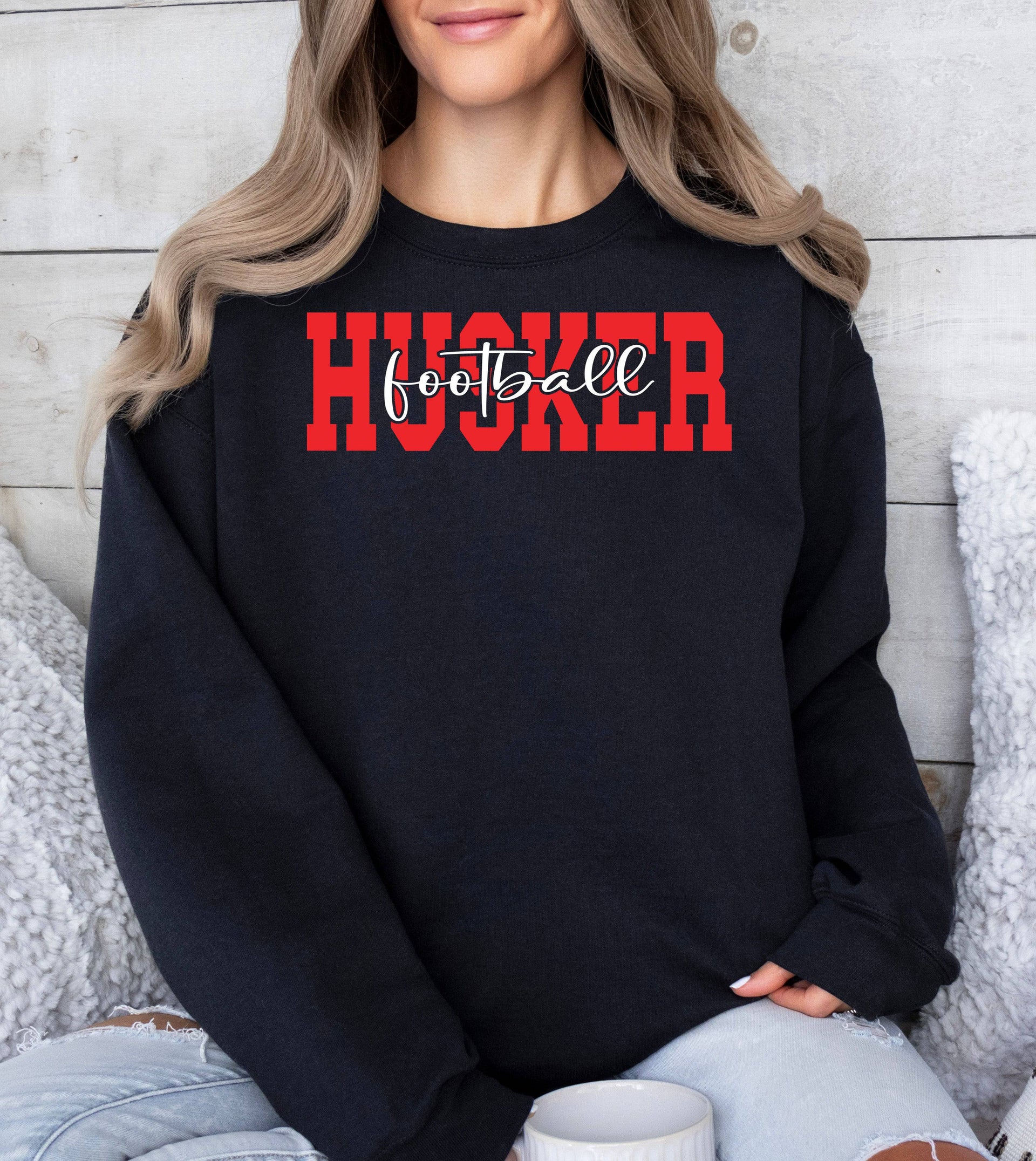 Woman wearing a black Husker Football crewneck sweatshirt.
