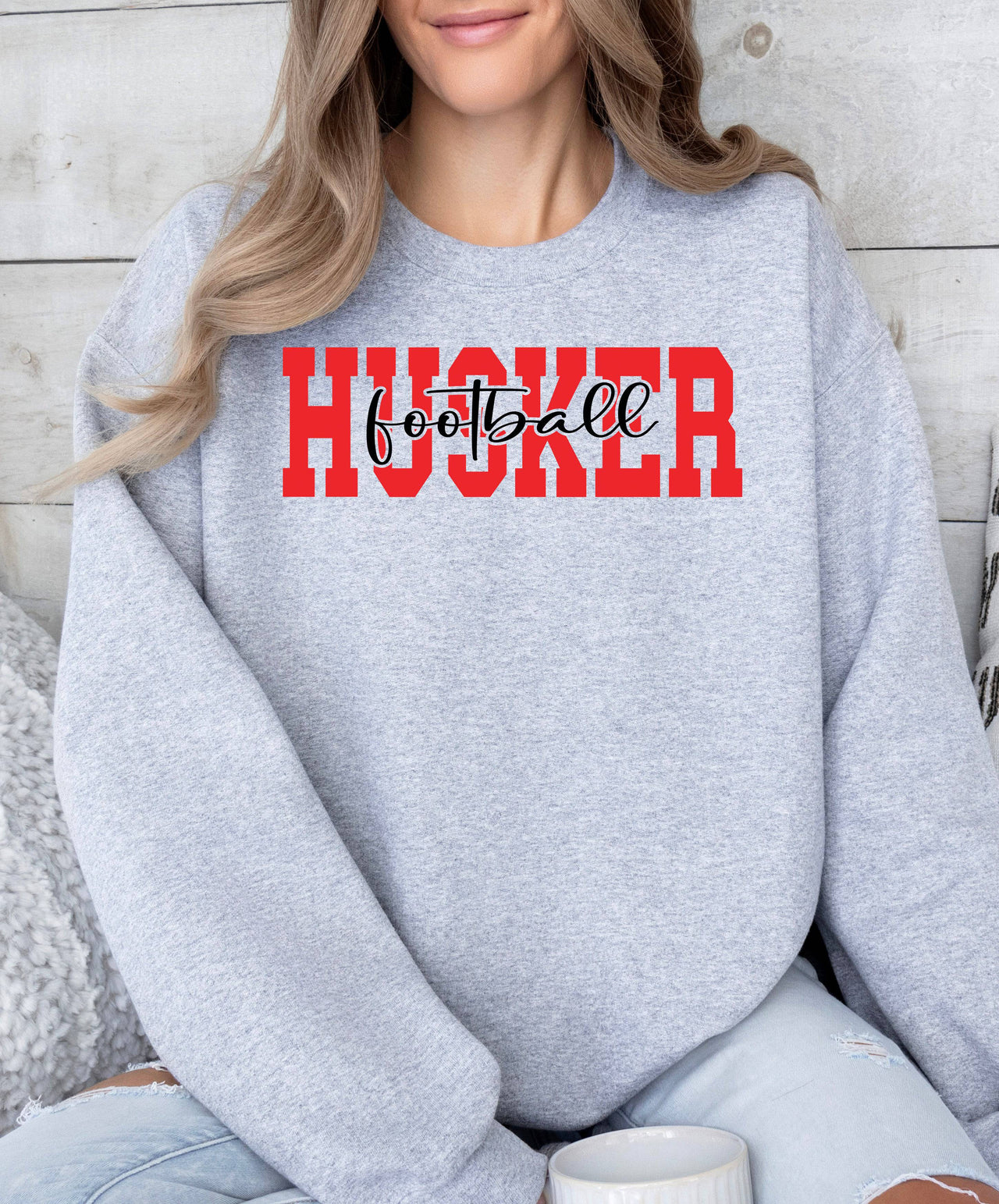 Woman wearing a sport grey Husker Football crewneck sweatshirt.