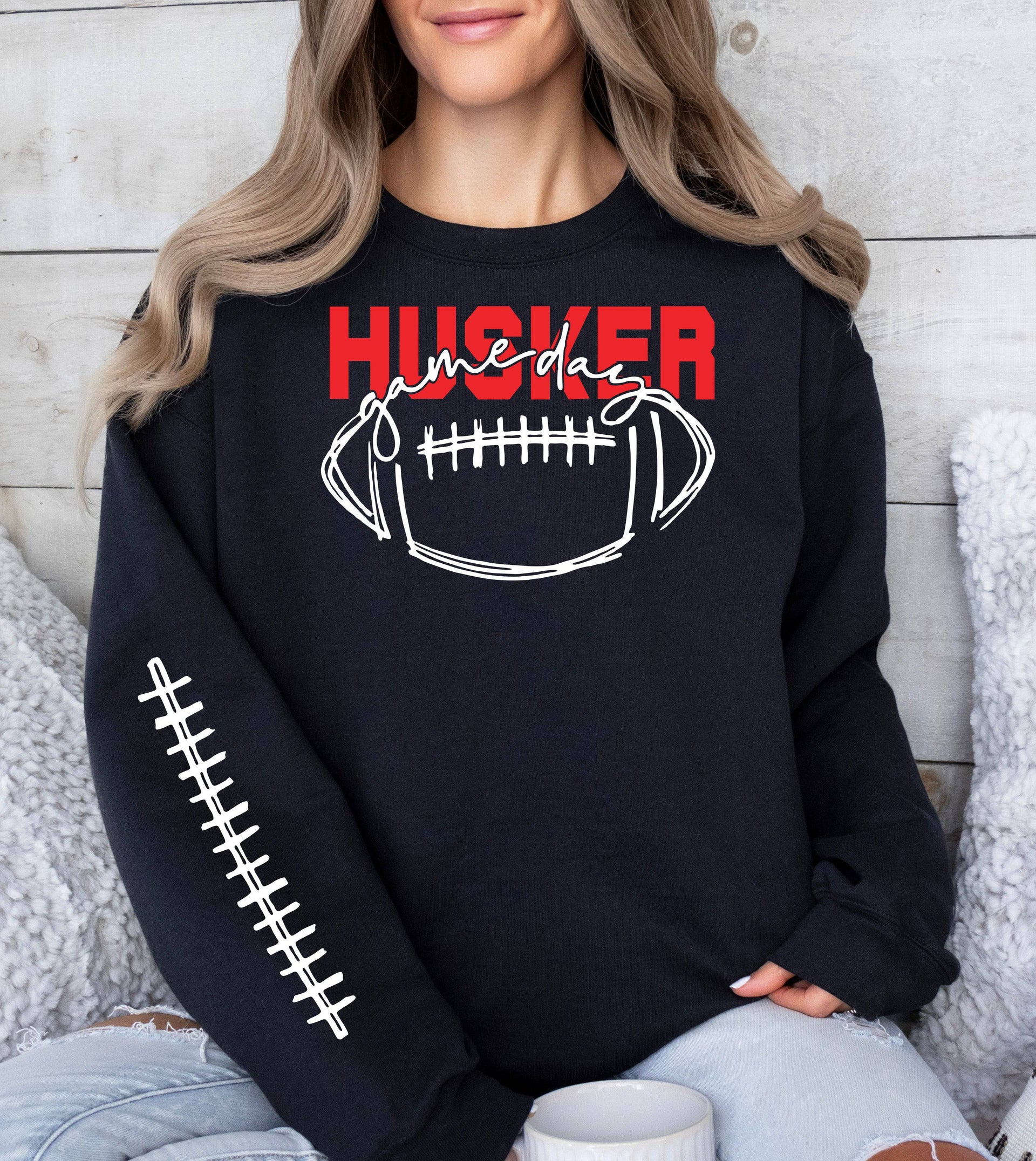 Woman wearing a black Husker Game Day crewneck sweatshirt.
