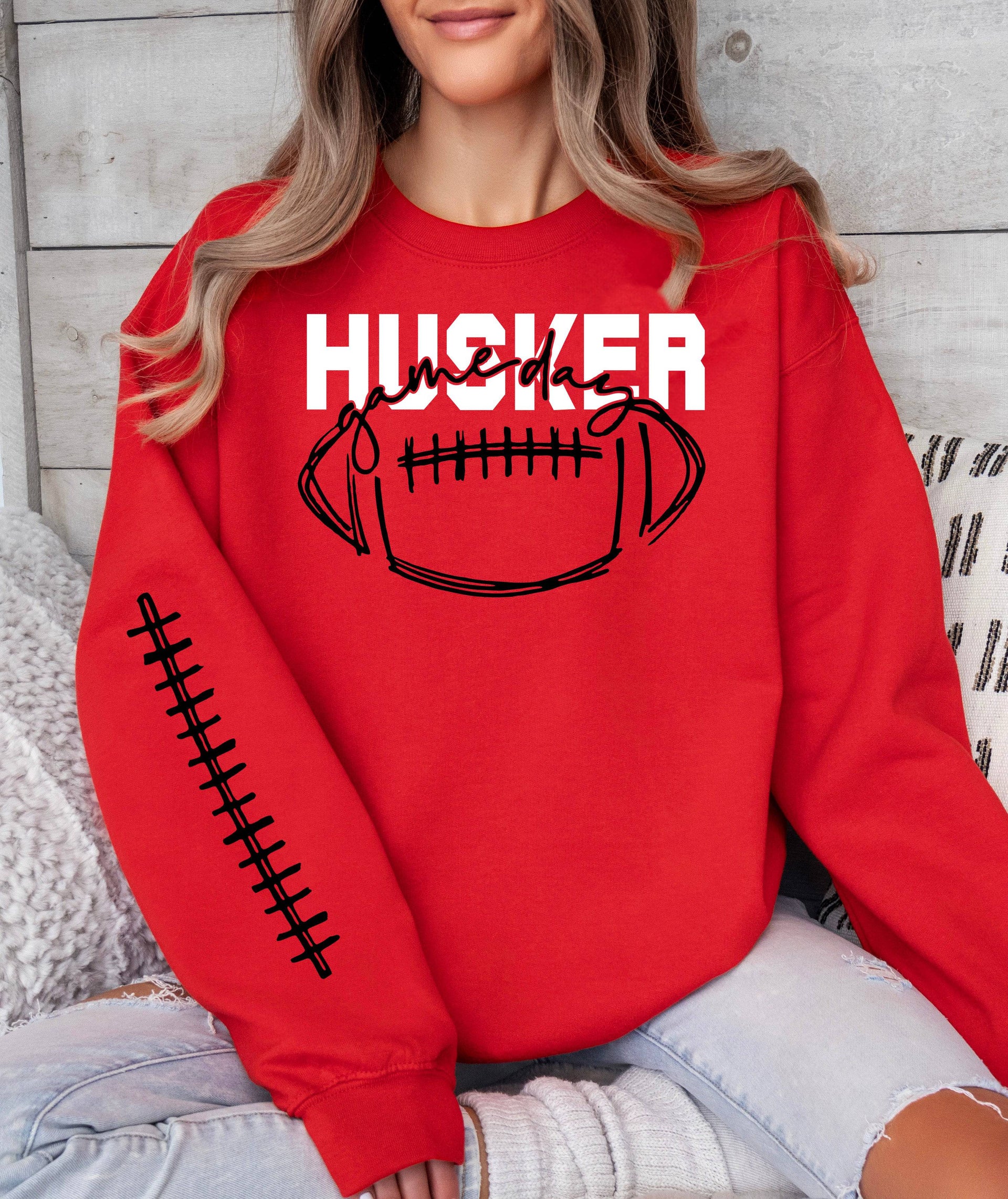 Woman wearing a red Husker Game Day crewneck sweatshirt.