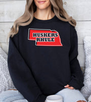 Woman wearing a black Huskers Rhule crewneck sweatshirt.