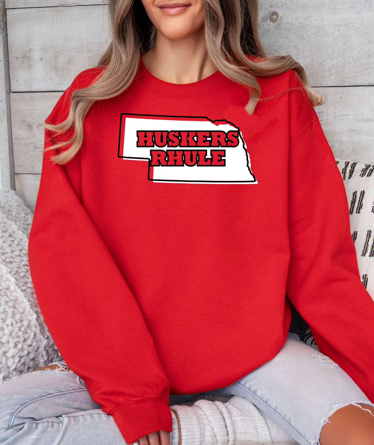 Woman wearing a red Huskers Rhule crewneck sweatshirt.