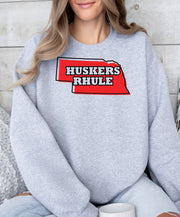 Woman wearing a sport grey Huskers Rhule crewneck sweatshirt.