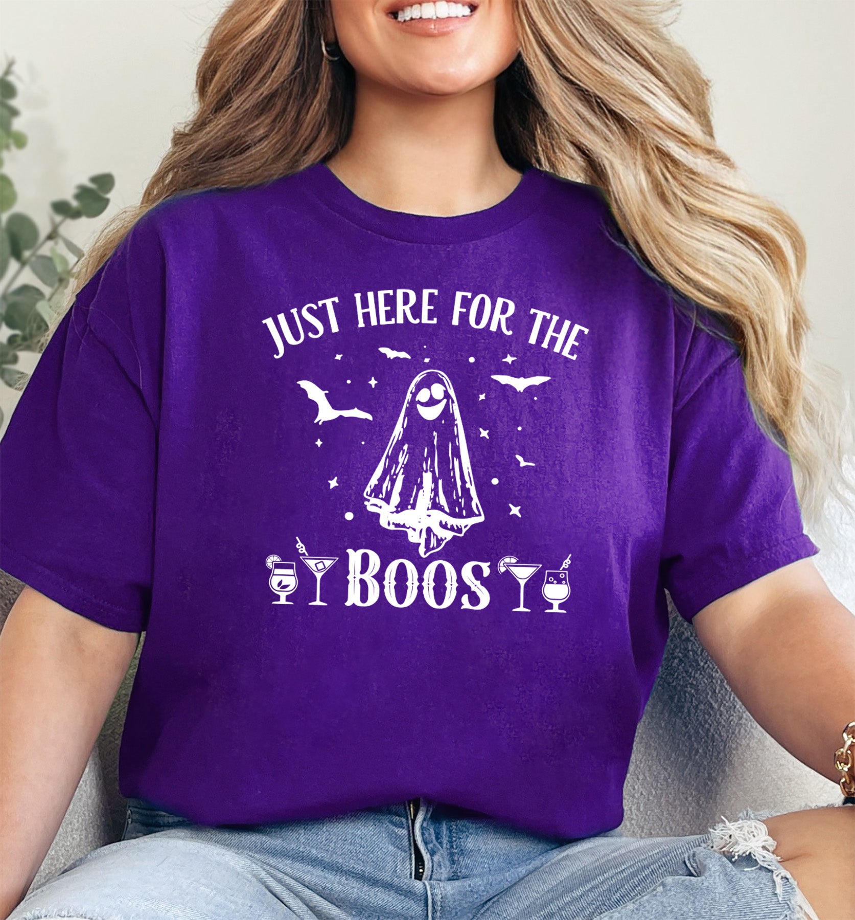 A person wearing a purple t-shirt with 'I JUST HERE FOR THE BOOS' text and a graphic of a ghost on the front.