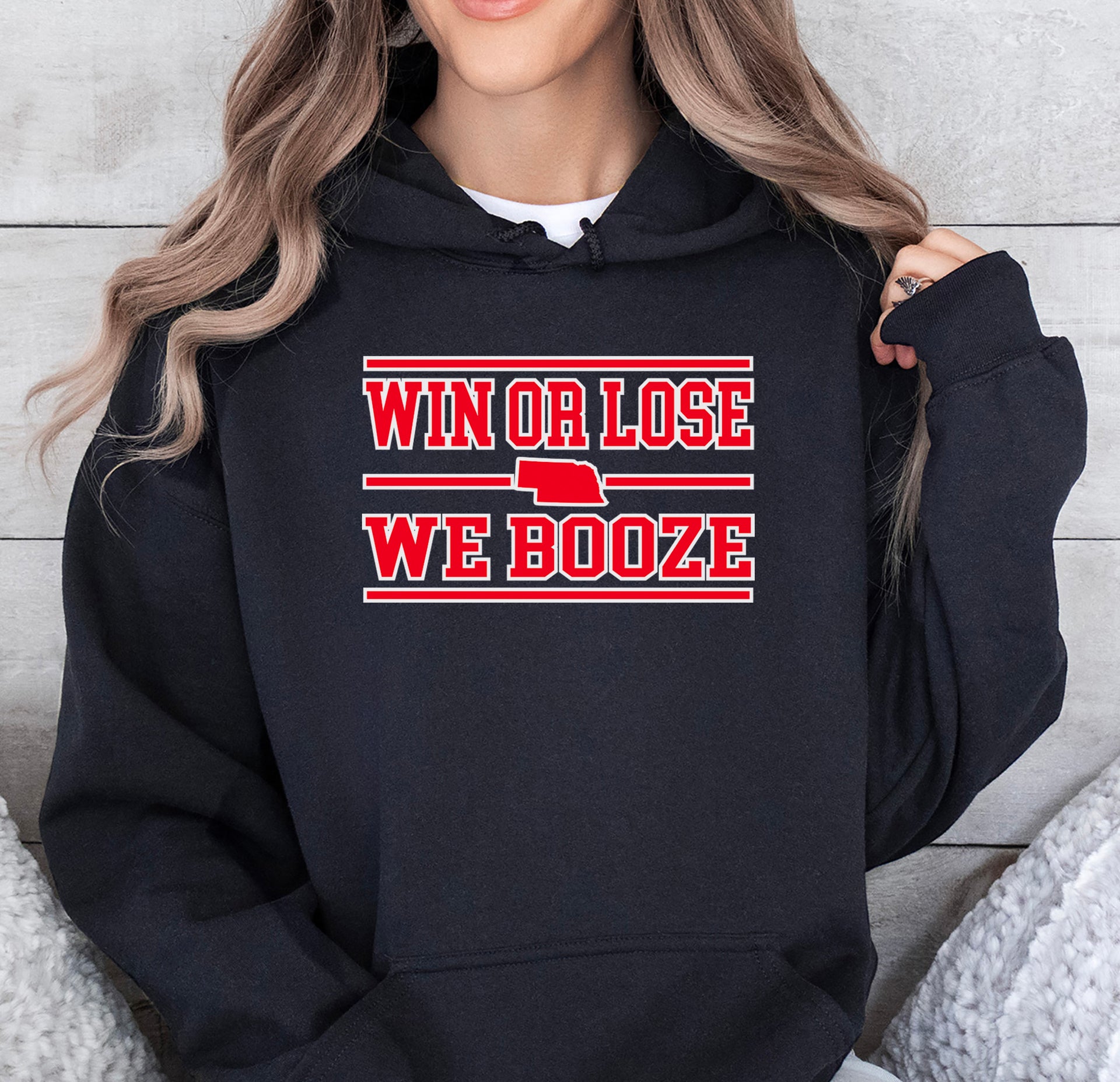 Person wearing a black hoodie with 'Win or Lose, We Booze' text design