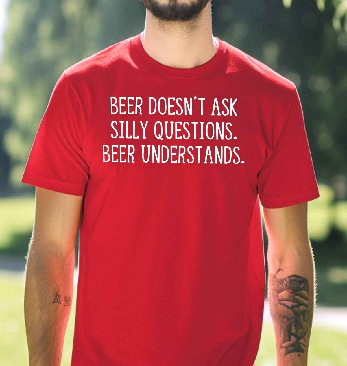 Man wearing a red graphic T Shirt with white lettering reading Beer Doesn't Ask Silly Questions Beer Understands, a funny beer lover design.