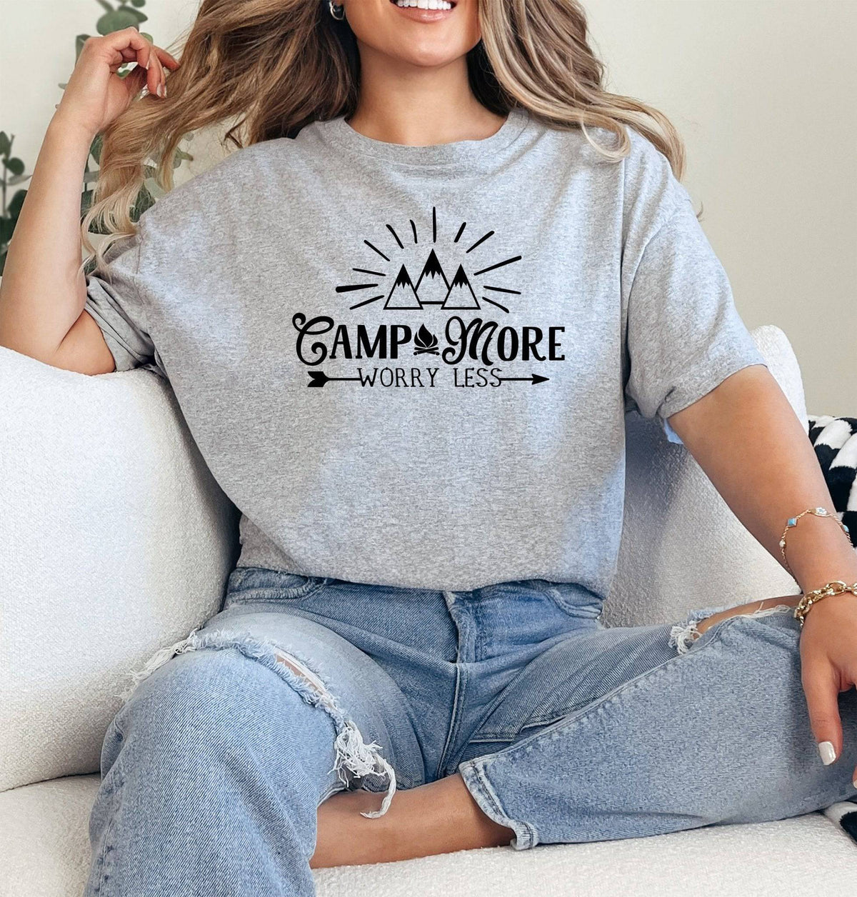 Woman wearing a Sport Grey Camp More Worry Less graphic T Shirt featuring a black mountain and campfire design with outdoor-inspired lettering.