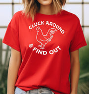 Woman wearing a red Cluck Around & Find Out graphic T Shirt featuring a white rooster illustration and bold lettering, perfect for chicken lovers and farm life fans.