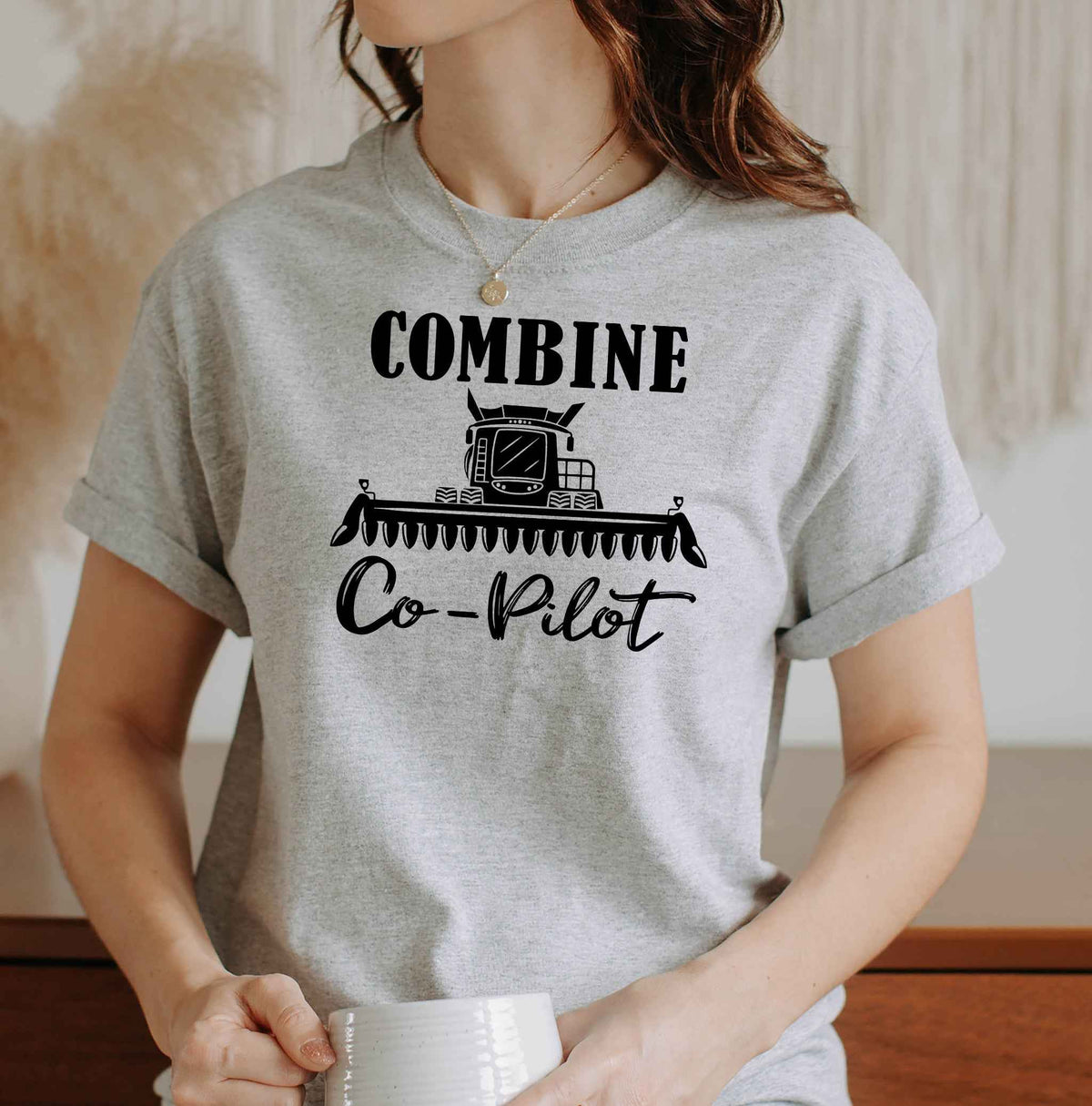Woman wearing a Sport Grey Combine Co-Pilot graphic T Shirt featuring a black combine harvester illustration and lettering, perfect for farm wives and harvest season.