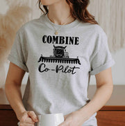 Woman wearing a Sport Grey Combine Co-Pilot graphic T Shirt featuring a black combine harvester illustration and lettering, perfect for farm wives and harvest season.
