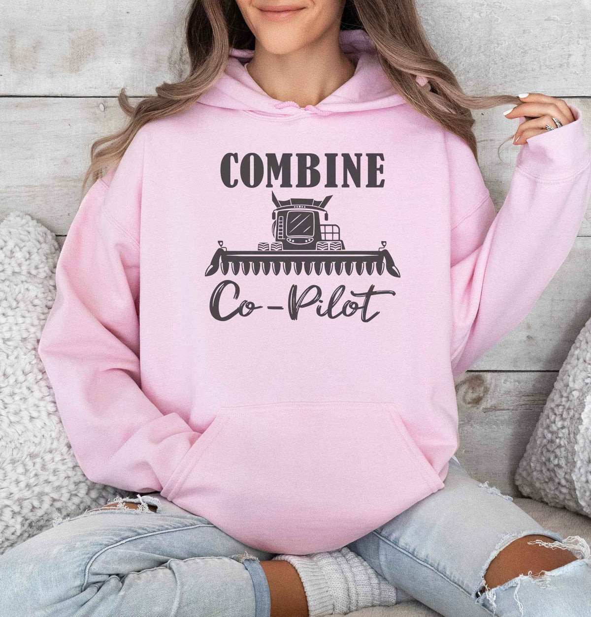 Woman wearing a Pink Combine Co-Pilot hooded sweatshirt featuring a dark combine harvester graphic and lettering, perfect for farm wives and harvest season.
