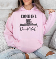 Woman wearing a Pink Combine Co-Pilot hooded sweatshirt featuring a dark combine harvester graphic and lettering, perfect for farm wives and harvest season.