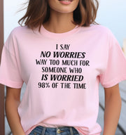 Woman wearing a pink I Say No Worries graphic T Shirt featuring a funny saying about worrying 98 percent of the time in bold black lettering.