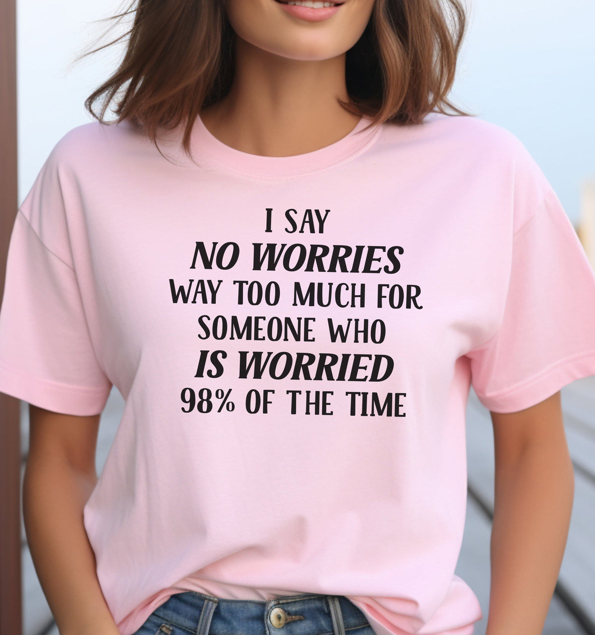 Woman wearing a pink I Say No Worries graphic T Shirt featuring a funny saying about worrying 98 percent of the time in bold black lettering.